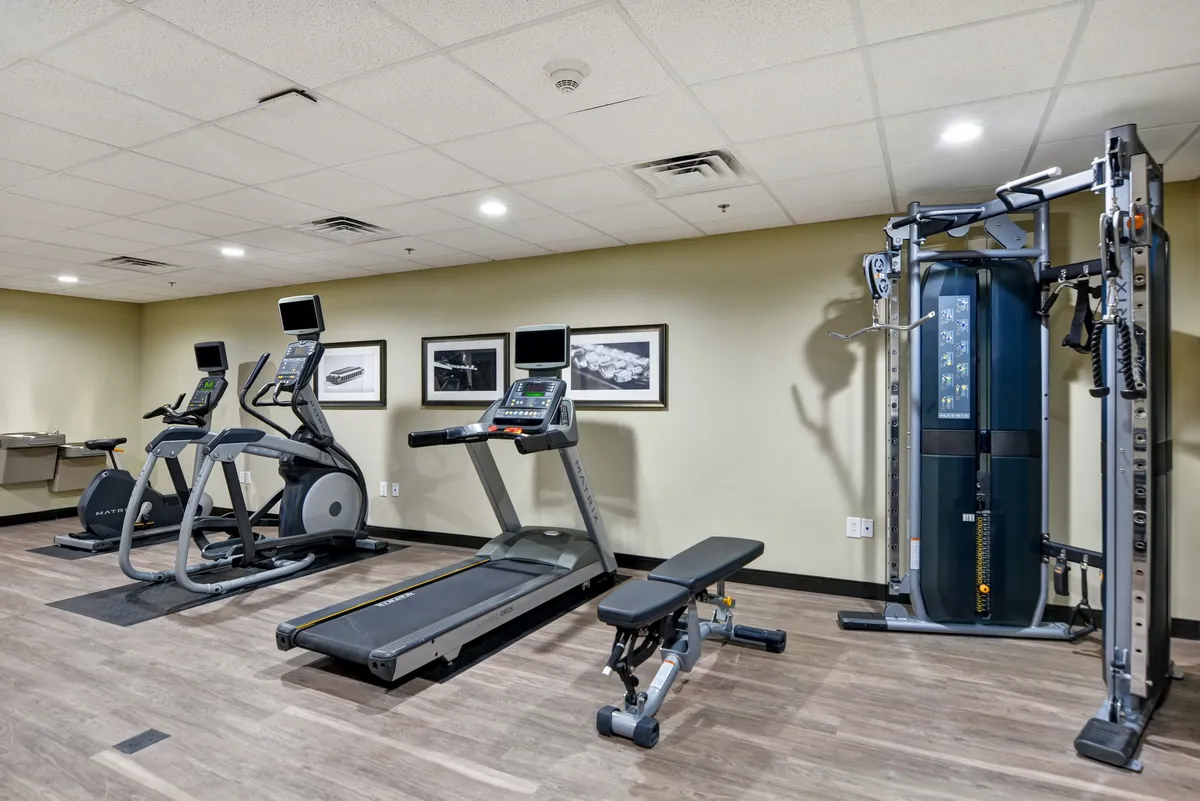 The fitness center features a range of cardio and strength-training equipment, including treadmills, elliptical machines, a weight bench, and a multi-gym machine. The room is well-lit, spacious, and clean, encouraging guests to maintain their workout routines during their stay.