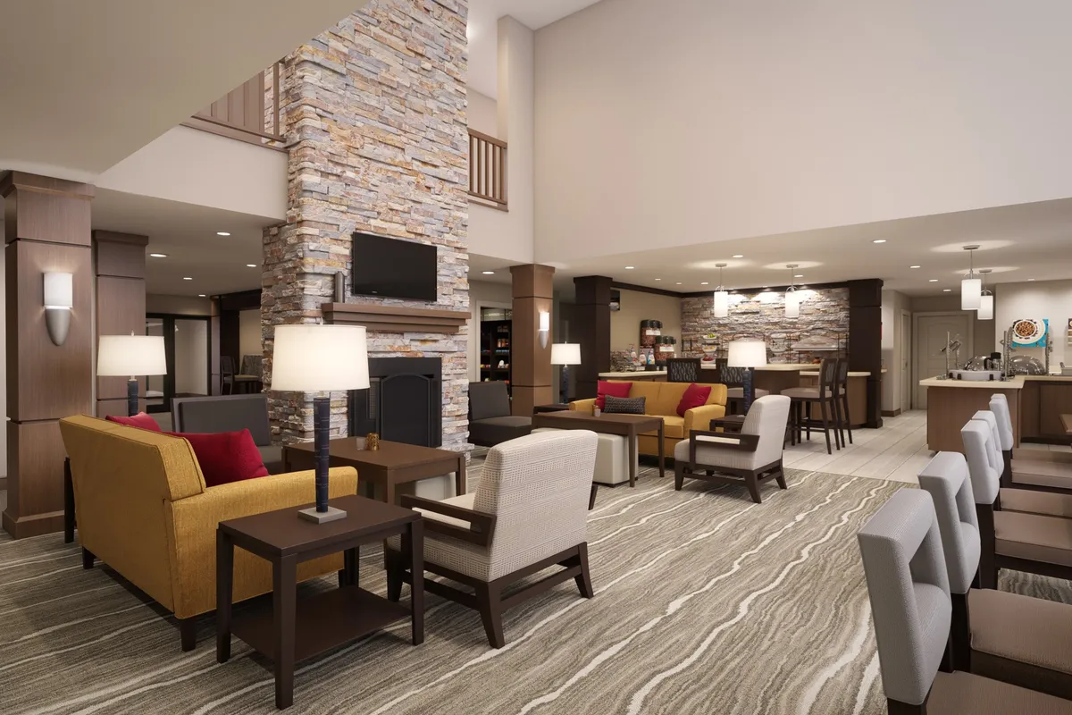 This interior scene features a stone fireplace, colorful seating, and a central bar area. Guests are seen socializing, relaxing, and enjoying refreshments, evoking a sense of cozy evenings and lively conversations.