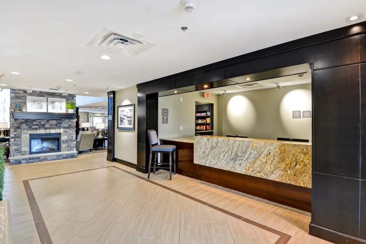The image captures the reception desk area with a cozy fireplace and a welcoming seating area. The space feels inviting and comfortable, with guests checking in and others relaxing by the fire, setting a tone of hospitality and warmth.