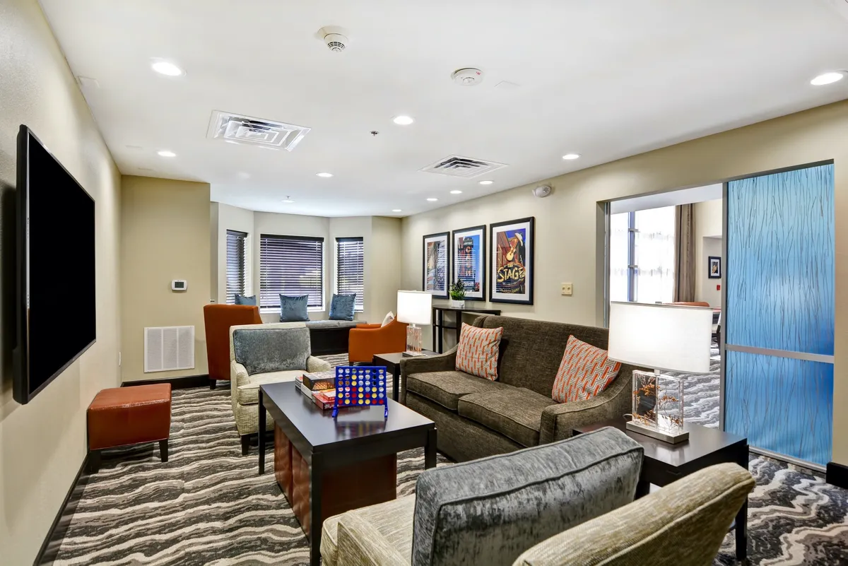 A comfortable living area is shown, with a sofa, coffee table, wall art, and soft lighting fixtures, creating a casual and homey atmosphere. The setup is suitable for relaxing, socializing, or enjoying quiet moments.