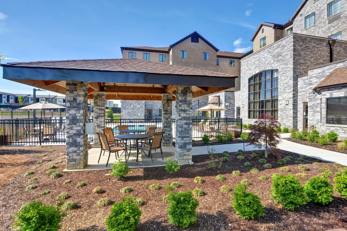 A view of the pool area complemented by a stylish stone gazebo and outdoor dining table, surrounded by landscaped gardens. This inviting scene suggests versatility—guests can enjoy poolside gatherings, quiet mornings with coffee, or festive dinners under the gazebo.
